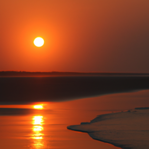 A beach with a bright orange sky and sun reflecting off of the ocean.