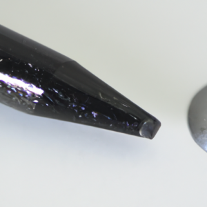 A close-up of a black eyeliner pencil tip with a shimmery metallic sheen.