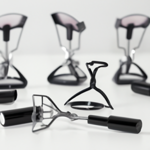 A set of eyelash curlers with a selection of mascara brushes in the background.