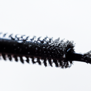 A close-up of a mascara wand with water droplets on it.