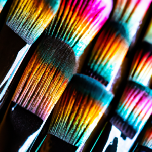 A close-up of a variety of colorful eye makeup brushes in an abstract pattern.