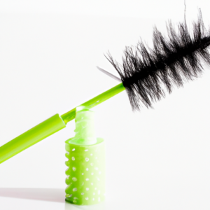 A lush green eyelash brush against a white background.