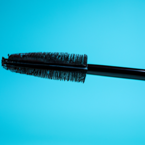 A close-up of a mascara brush against a light blue background.