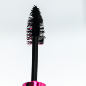 A close-up of a pink and black mascara wand with multiple bristles.