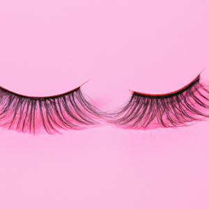 A close-up of a set of long eyelashes with a pink background.
