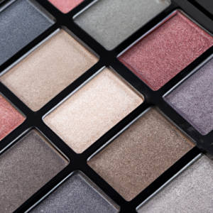 A close-up of a smoky eye makeup palette with various colored eyeshadows.