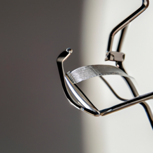 A close-up of a metal eyelash curler, glinting in the light.